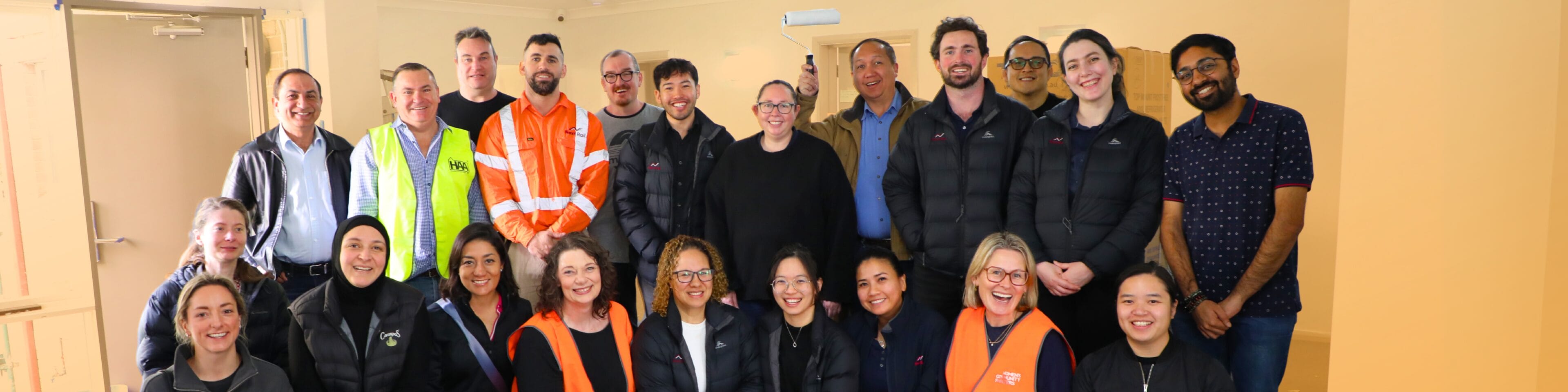 A cheerful group of individuals standing together for a photo in a bright room.