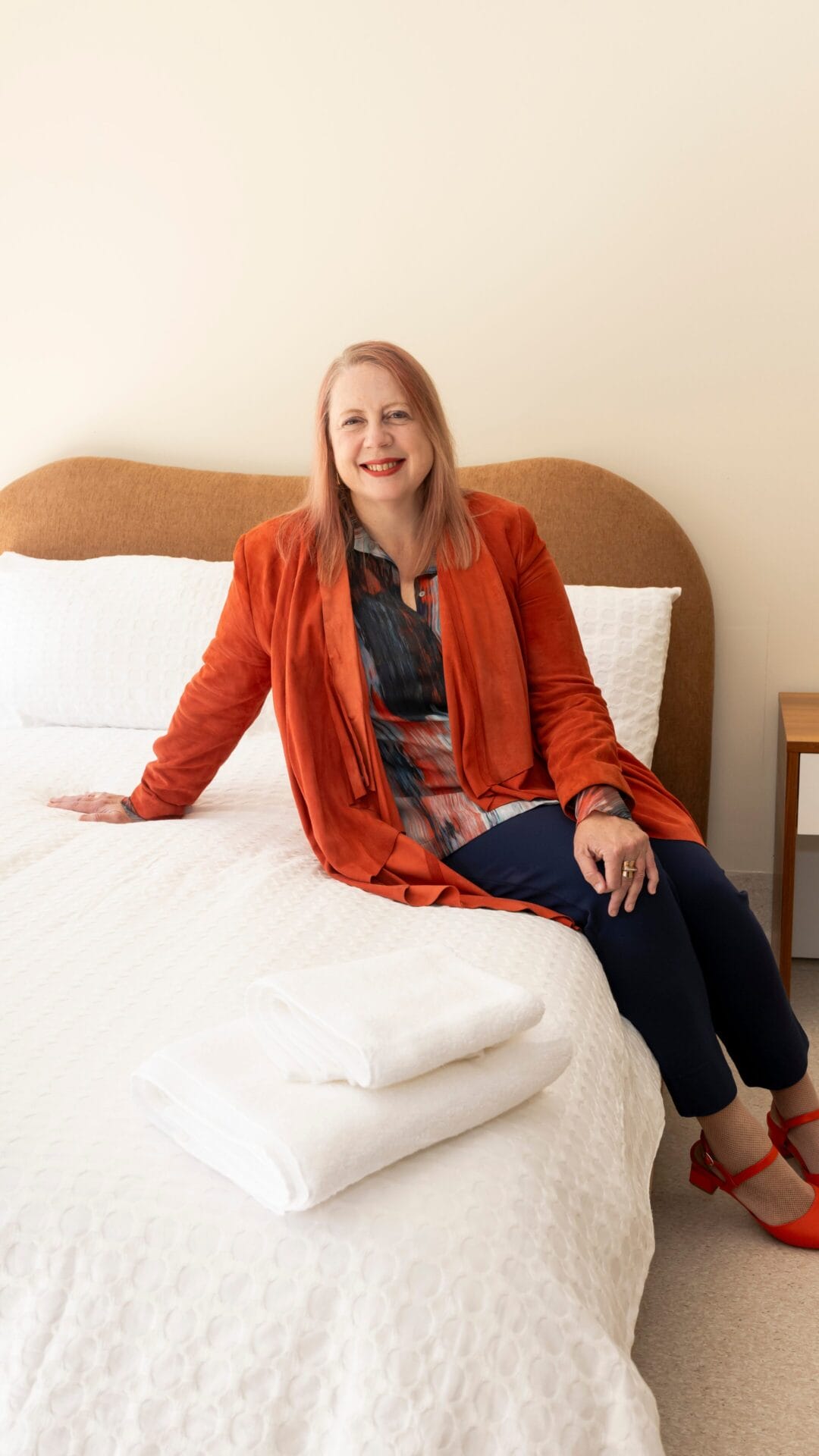 Annabelle Daniel, CEO of Women's Community Shelters, sitting thoughtfully on a bed in a cozy room.