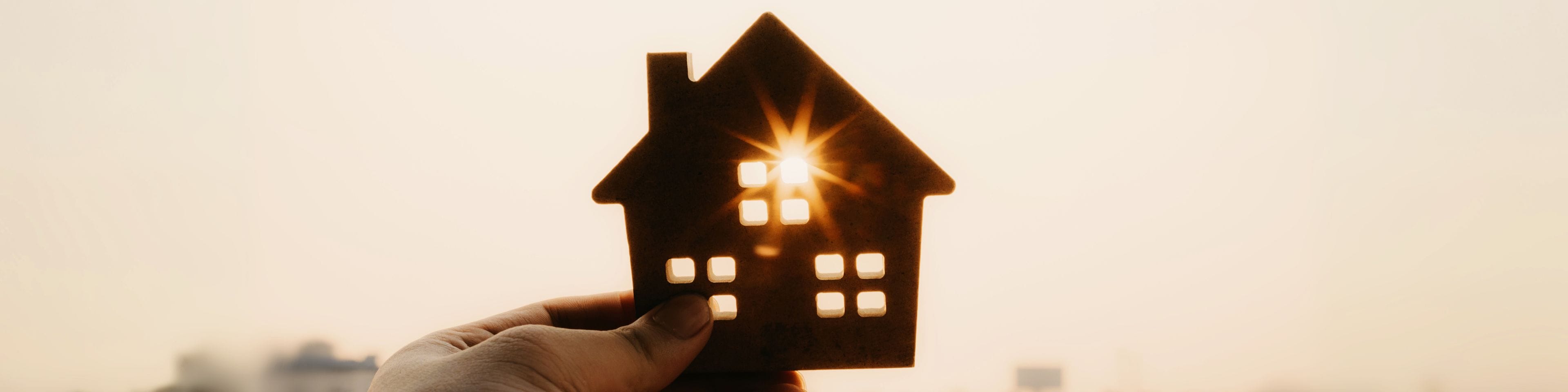 A house model in front of a city skyline.