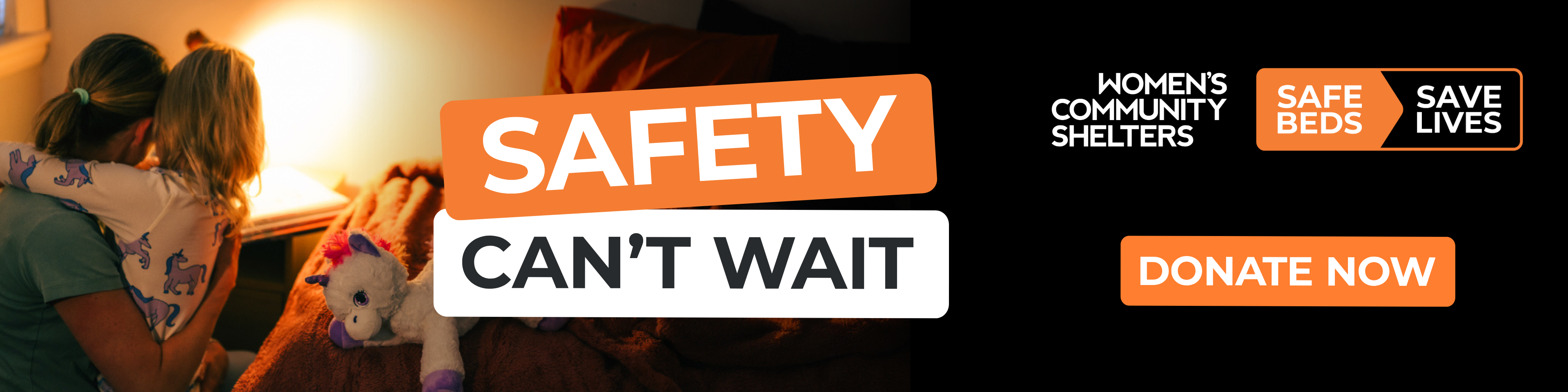 Mother holding a young child at night beside the Women’s Community Shelters “Safety Can’t Wait” Safe Beds Save Lives EOFY donation campaign banner